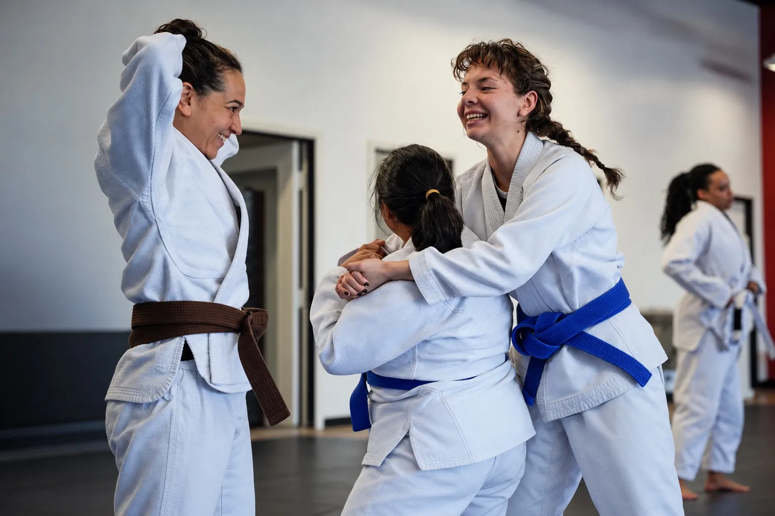 Women in white gis laughing together mid-drill