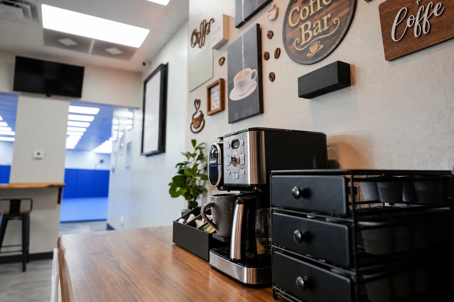 The coffee bar: a coffee maker and pod drawers on a wooden counter, coffee signs on the wall