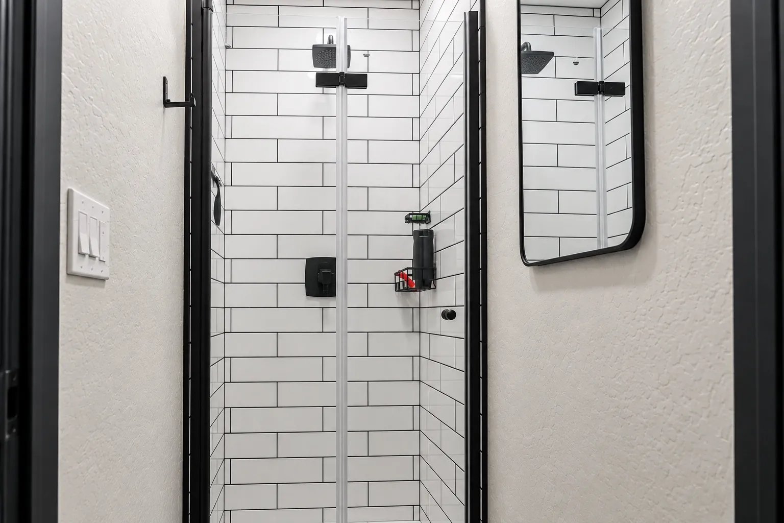 A private shower with white subway tile and black fixtures