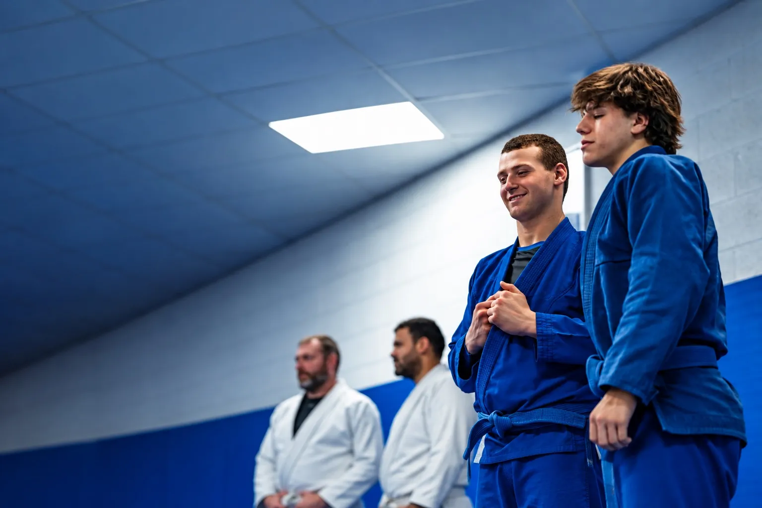 Two teenagers in blue gis laughing together on the mat